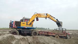 New Hitachi excavator loading tractor trolley with sand at river||new hitachi excavator