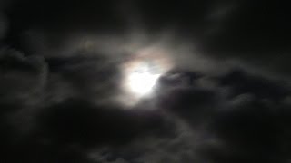 Storm clouds blowing past the full moon at night