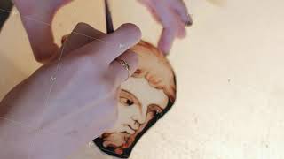 Close-up. The artist paints with a brush on the details of the stained-glass window. Art workshop