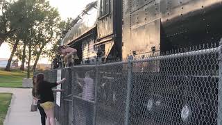 Woman jumping over fence. Big Boy Steam Engine