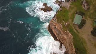 Ocean waves crashing and hitting against cliff and rocks bird eye view aerial drone shot FREE STOCK