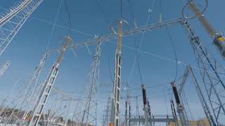 Poles and cables of power plant in winter. Action. Power plant in field on sunny winter day