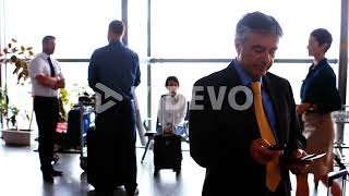 Businessman using mobile phone while commuters interacting with each other