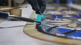 Close-up Soldering stained glass seams. Gloved hands with a soldering iron. Stained glass workshop