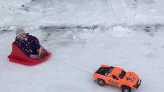 Traxxas Slash with chains towing a sled with the baby