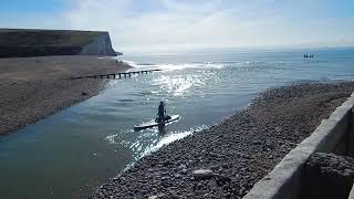 Cuckmere Sussex, the river joins the English Channel, paddleboarders and lapping waves, 2024.