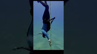 Female freediver swims to the bottom and folds her arms