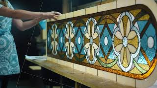 Two female artists in the stained glass workshop are completing the production of the stained glass