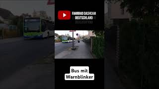 Kraftfahrzeuge rasen an Bus mit Wanblinker vorbei