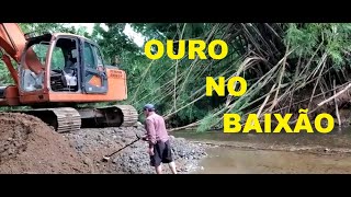 Escavadeira mexendo na estrada e saindo ouro na escavação e dentro rio.