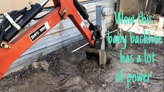 Mini backhoe digging up a sewer pipe