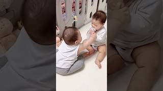 Baby twins sit and suck on a spoon