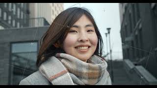 Close-up of an Asian girl smiling happily against the backdrop of city buildings. A young girl with