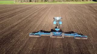 New Holland tractors ploughing and rolling the fields, viewed from the sky.