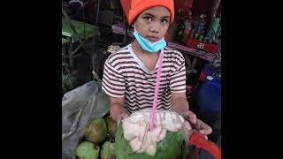 Young girl taught by His lolo how to part coconut and sell