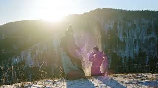 Young parents play snowballs with their young sons on the top of the mountain.