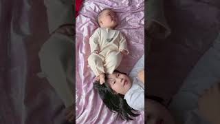 Baby puts her feet on her sister's head