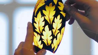 Artist's hands with part of stained glass sketch. The artist looks at the light part of the stained