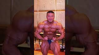 Massive Chinese muscle bull flexing in dark blue posing trunks