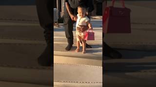 STORMI WEBSTER CAN’T LET GO OF HER DESIGNER BAG AS SHE TAKES HER FIRST STEPS