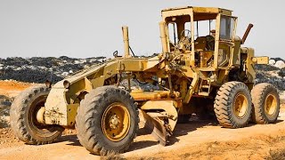 The yellow grader spreads small gray pebbles on the road