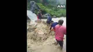 People trying to cross Amlawa River via a temporary bridge, which was damaged due to heavy rainfall,