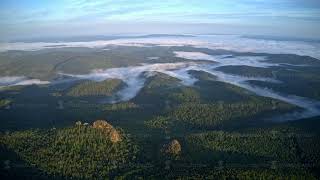 Top view of the mountains in the fog in the Russian nature Reserve Stolby. Aerial timelapse