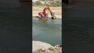 An eye-catching image of the Excavator Lifts Floating Concrete Pipe from River with Precision