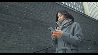 Asian woman with a smartphone going down the stairs on the background of business buildings. Prints