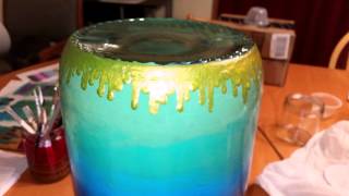 Painting bronze colored drips on a glass jug.