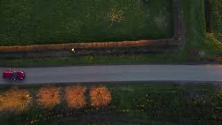 Aerial drone shot slowly zooming out of alpha romeo car driving by in nature FREE STOCK VIDEO