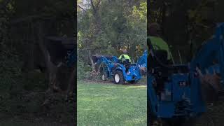 Compact tractor mowing down trees