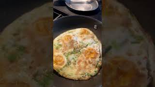 Flipping organic eggs onto plate. Eggs, green onions, spices, extra-virgin macadamia oil.