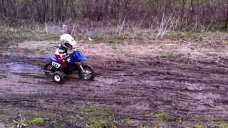 A 3 year old riding his dirt bike through mud