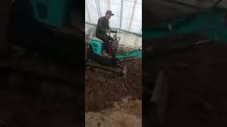 China mini excavator 1 ton doing earthmoving work in the greenhouse.