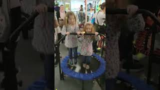 Two Kids Bouncing Happily on Trampoline with Safety Handle, Having Fun at the Exhibition!