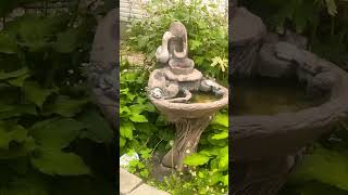 A wonderful statue of a duck standing on a fountain in front of a house