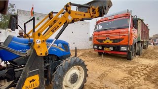 Truck stuck in sandy soil pulled out with tractor