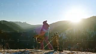 A mother is having fun with her sons on top of a mountain at sunset.