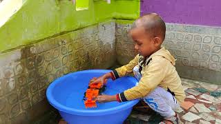 Tanbir is washing the orange color JCB.