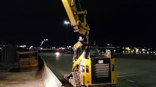 Caterpillar 335 lifting a 289 over k-rail with a hook