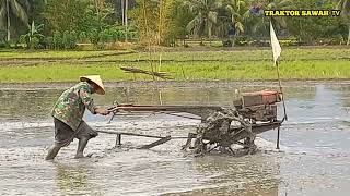 joki senior berbaju loreng meratakan tanah menggunakan traktor sawah cepat hasilnya memuaskan