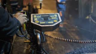 Close-up of a road worker clicks on the buttons on the paver's control panel. Repair of roads at