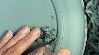 Trimming a green stoneware dinner plate on the pottery wheel