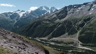 Amazing landscape with giant mountains with green slopes and snowy peaks. Clip. Stony trail along