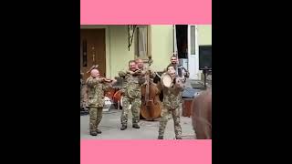 People cheering as a Ukrainian army band performs on a street as the country faces Russian invasion.