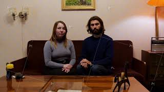 Portrait of young soviet couple watching television on the sofa, looking straight to the camera