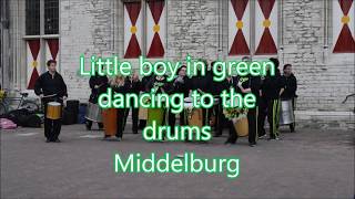 Little boy in green dancing to the rhythm of the drums