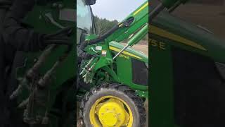 John Deere tractor moves a round bale