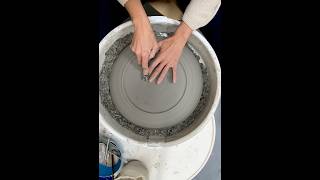 Trimming a large stoneware platter on the pottery wheel